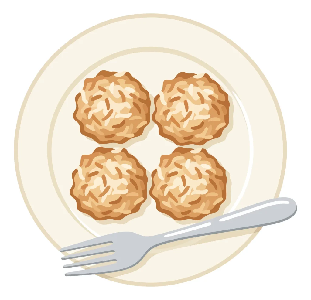 top view of four coconut macaroons on a white plate with a silver fork