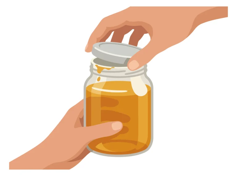 A hand pouring honey from a clear glass jar into another container
