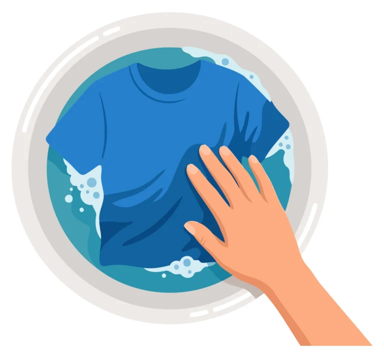 A hand holding a blue t-shirt inside a washing machine with water bubbles