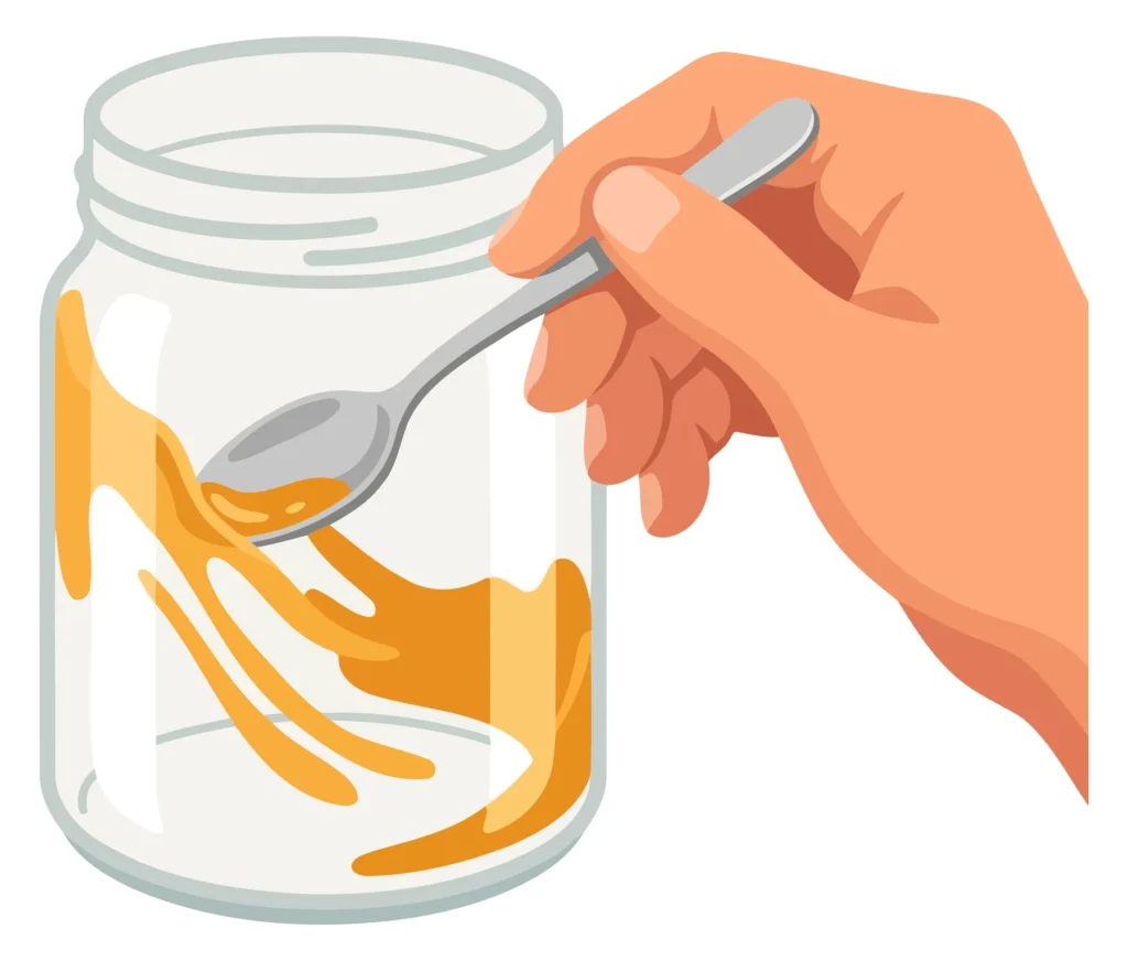 A hand scoops orange-colored sauce from a glass jar with a spoon